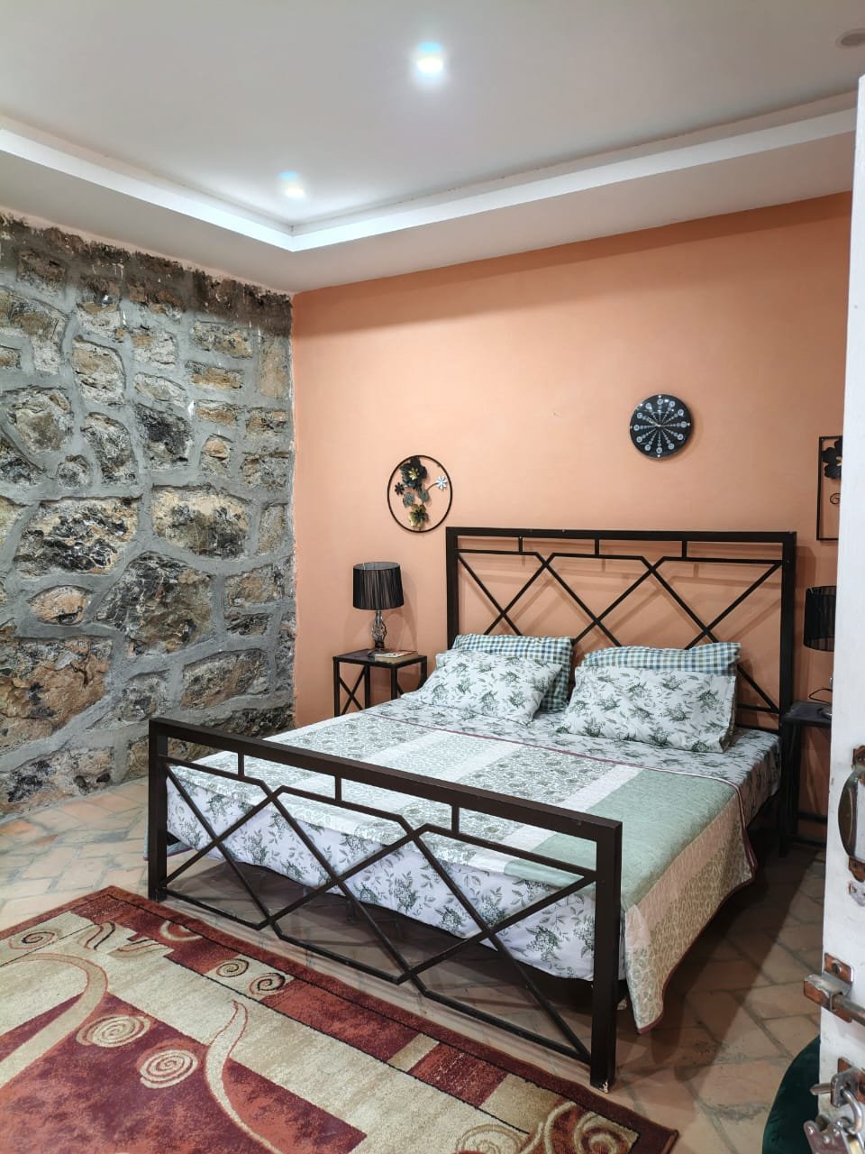Bedroom with a natural stone feature wall and iron bed frame